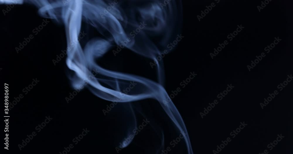 White smoke floating through space against black background White smoke floating through space against black background