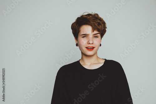 The girl stands on a white background and shows emotions