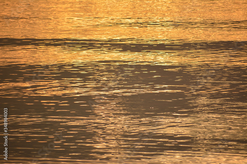Water ripples background illuminated by orange sunlight during a sunrise over the Chesapeake Bay