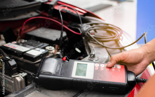 The mechanic uses the equipment to check the voltage of the car batteries in the service center and the motor vehicle repair center.