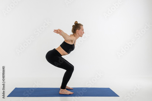 Sporty attractive young woman doing yoga practice on white background. Kursiasana.