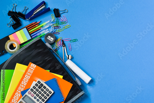 Backpack with school supplies. Concept back to school. Top view of colorful school supplies on a blue background. Place for text