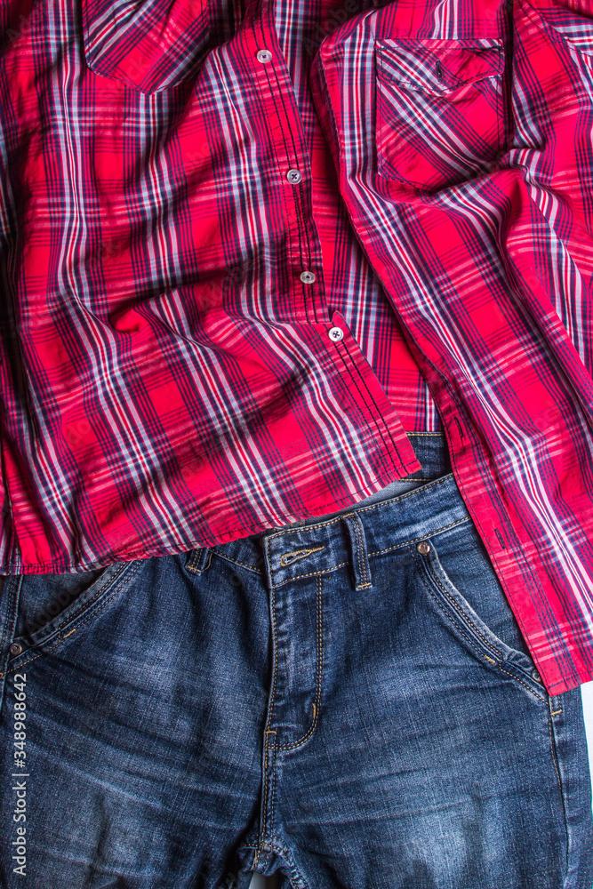 At the top of the photo lies a red checkered shirt. At the bottom of the photo are jeans. Photo above
At the top of the photo lies a red checkered shirt. At the bottom of the photo are jeans. Photo above