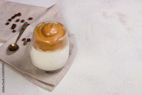 Dalgona Coffee in a transparent cup at white slate table top.