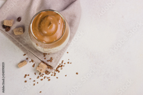 Dalgona Coffee in a transparent cup at white slate table top.