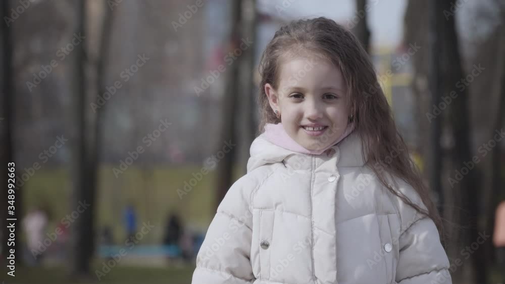Portrait of cute Caucasian little girl pulling ears and showing tongue. Funny brunette child with brown eyes grimacing outdoors on sunny autumn day. Leisure, fun, joy, lifestyle. Portrait of cute Caucasian little girl pulling ears and showing tongue. Funny brunette child with brown eyes grimacing outdoors on sunny autumn day. Leisure, fun, joy, lifestyle.