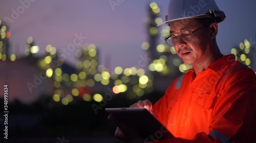 Slow motion shot of Asian engineer man using digital tablet working late night shift at petroleum oil refinery.
