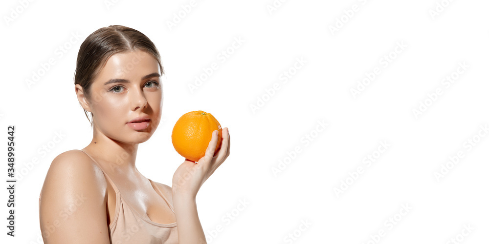 Portrait of beautiful young woman with fresh orange near face over white background. Concept of cosmetics, makeup, natural and eco treatment, skin care. Shiny and healthy skin, fashion, healthcare. Portrait of beautiful young woman with fresh orange near face over white background. Concept of cosmetics, makeup, natural and eco treatment, skin care. Shiny and healthy skin, fashion, healthcare.