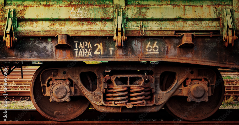 Close up fragment of old rusty train cargo wagon. Rusty wheels of an old rail car with weathered peeled green paint. Industrial conceptual scene with trains. Close up fragment of old rusty train cargo wagon. Rusty wheels of an old rail car with weathered peeled green paint. Industrial conceptual scene with trains.