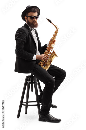 Bearded musician holding a saxophone and sitting on a chair