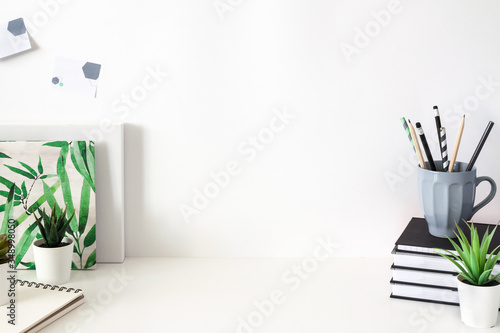 Home desk with office supplies. White blank wall copy space.