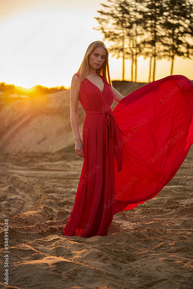 Beautiful fashion girl among the sands at sunrise
