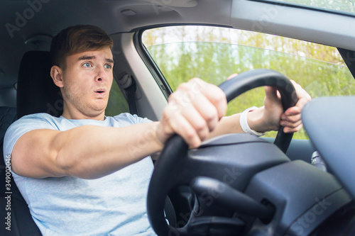 Cuadro en lienzo Handsome frightened fearful guy, driver, young scared man shocked about to have traffic accident, driving car on road holding steering wheel of automobile