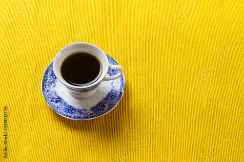 Chinese porcelain coffee cup on top of yellow placemat.