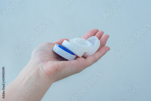 on a female hand are white and blue plastic bottle caps. Ecology and pollution of planet Earth. recycle concept
