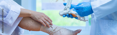 close-up hand wear medical gloves doctor in medical gloves holds artificial boneof the foot and examines a sore leg with a heel spur on a woman, close-up, osteophytes and heel, fascia