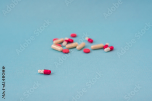tablets or capsules of white and pink color are scattered on a blue surface. antibiotic.