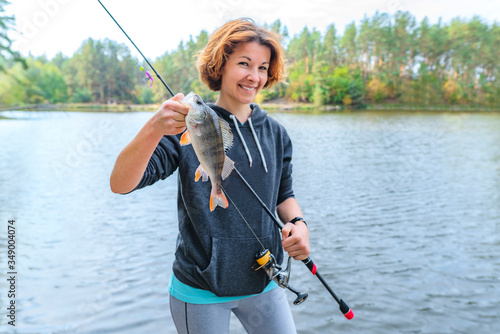 Success perch fishing. Lady fisherwoman with fish at lake