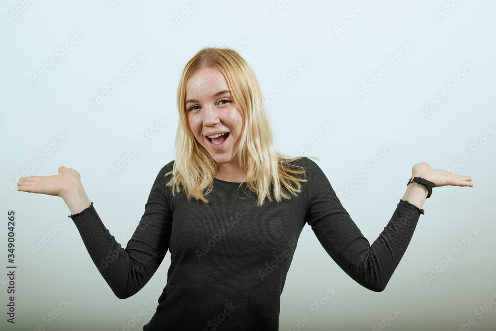 Young Blonde Woman In Black Sweater With Stylish Watch On White Background, Happy Attractive Girl Smiling Holding Her Hands Wide, Hands Palms Up. The Concept Of Confident, Cheerful People Young Blonde Woman In Black Sweater With Stylish Watch On White Background, Happy Attractive Girl Smiling Holding Her Hands Wide, Hands Palms Up. The Concept Of Confident, Cheerful People