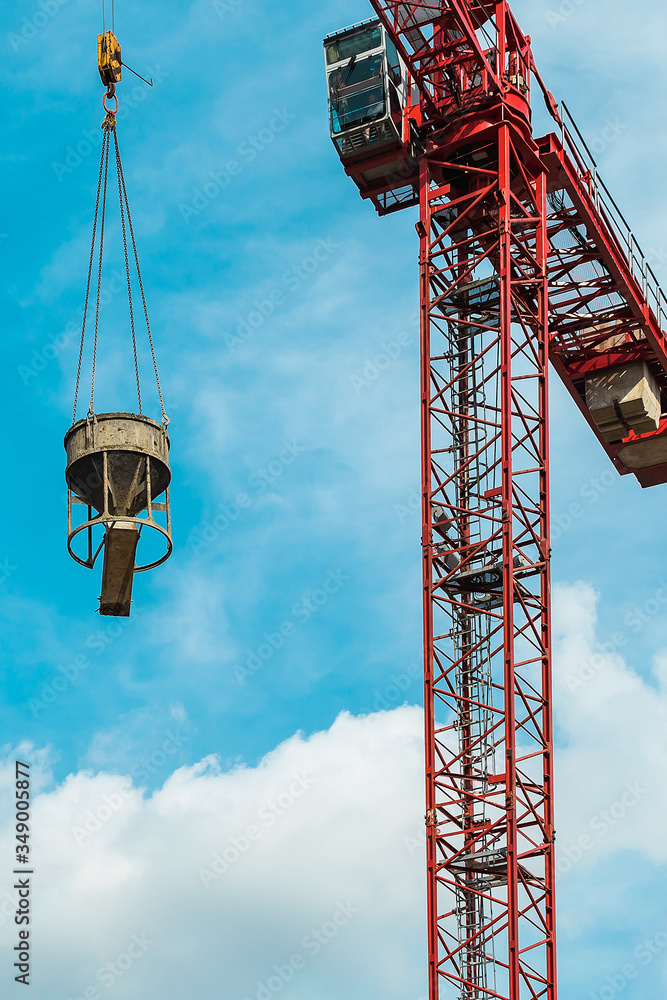Red tower crane with cement mixer against turquoise sky with white clouds. Close up. Copy space. Red tower crane with cement mixer against turquoise sky with white clouds. Close up. Copy space.