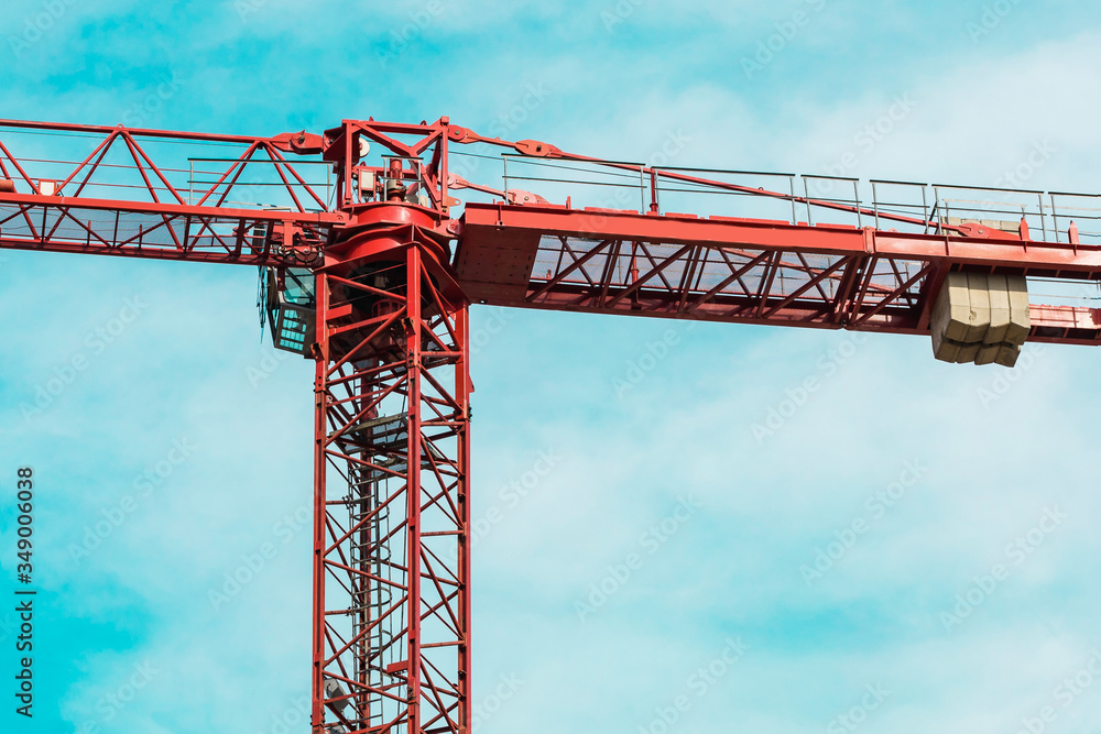 Red tower crane in horizontal position arrows against turquoise sky with white clouds. Close up. Copy space. background