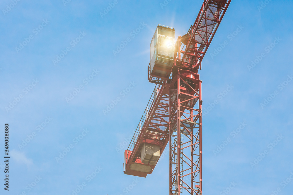 Red tower crane with glare against blue sky with white clouds. Close up. Copy space. Red tower crane with glare against blue sky with white clouds. Close up. Copy space.