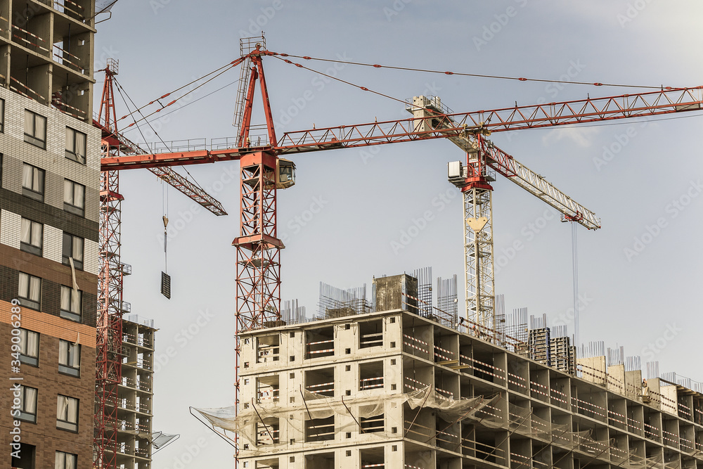 Several red cranes have been put to work on the construction of a modern multi-storey residential complex. Concept work for people with the profession of builder. Large construction site. Several red cranes have been put to work on the construction of a modern multi-storey residential complex. Concept work for people with the profession of builder. Large construction site.