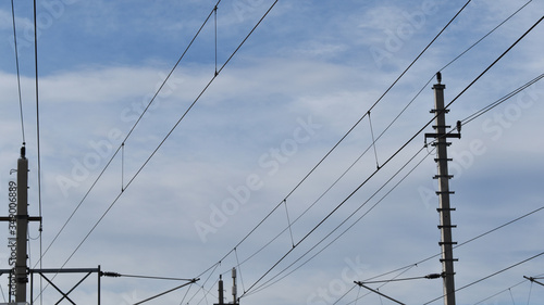 Stromleitungen und Masten vor blauem Himmel und Wolken