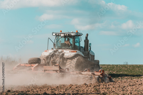 Wallpaper Mural Rear view of a crawler tractor during sowing. Harrowing soil in the field. Torontodigital.ca