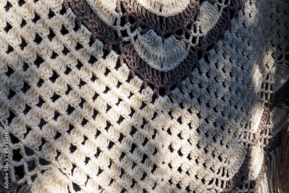 Close-up of knitted shawl wool of beige and brown color. Textured background, selective focus.