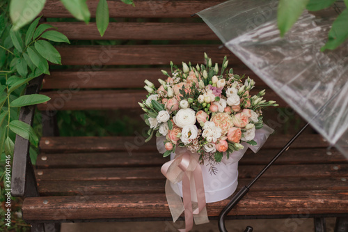 A large flower arrangement in a big white hat box in rainy day was created by a florist for a wedding gift. white freesia   ranunculus asiaticus  eustoma flowers  roses and eucalyptus in flowers box