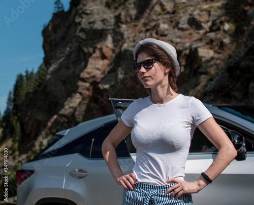 Lifestyle portrait of a stylish girl near the car and a beautiful mountain landscape in the backgroundCarefree lifestyle and travel concept