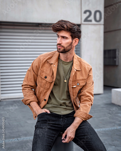 Handsome modern man sitting on the street in city, Male fashion model dressed casually.