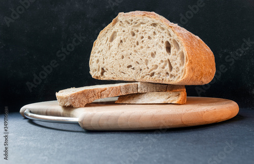 Beautiful bread made from rye and wheat flour on a wooden board on a black background. Sliced slices and half bread.