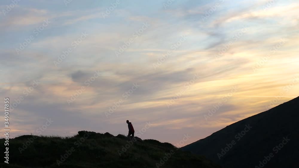 Dark silhouette of a hiker climbing a mountain at sunset reaching summit like a winner. Dark silhouette of a hiker climbing a mountain at sunset reaching summit like a winner.