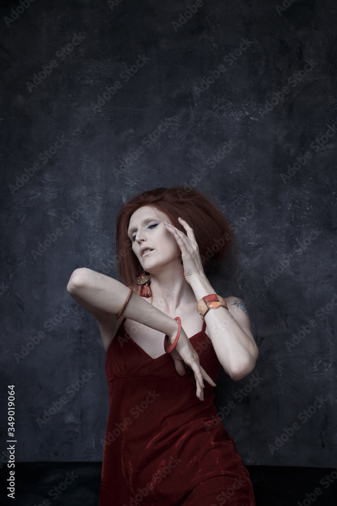 A woman with pale porcelain skin and a lush hairstyle posing on a gray painted background like a doll. A woman with pale porcelain skin and a lush hairstyle posing on a gray painted background like a doll.
