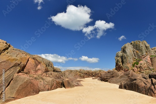 Jersey, U.K. Rocky beach with fair weather clouds.