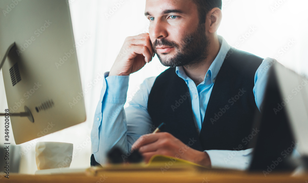Naklejka premium businessman looking in monitor computer at home workplace. man drinking coffee working at social distance, freelancer online communication, online education process