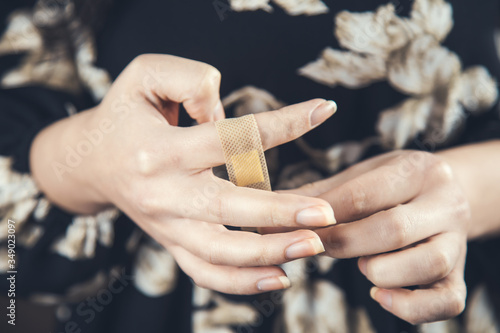Woman using medical plaster on finger