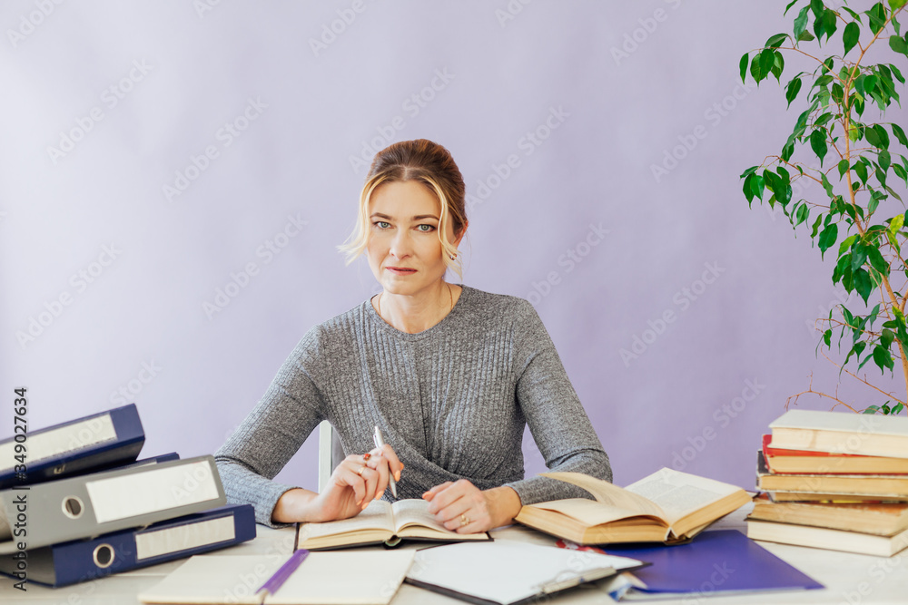 beautiful business woman sits at desk with teacher's books beautiful business woman sits at desk with teacher's books