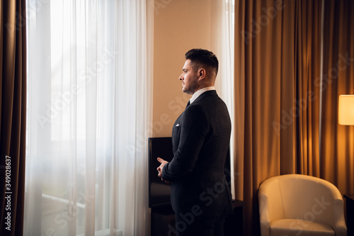 Side view of a bridegroom standing in a hotel room waiting for t