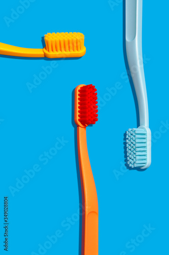 Modern Monochromatic Yellow, Orange and Blue Toothbrushes Layout on Blue Background (ID: 349028804)