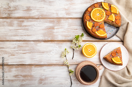 Orange cake and a cup of coffee on a white wooden background. Top view, copy space.