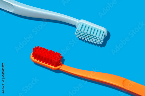 Modern Monochromatic Orange and Blue Toothbrushes Laying on Blue Background (ID: 349029877)