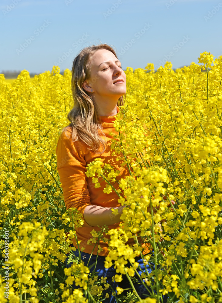 Portrait of a young woman with her eyes closed in a flowering rapeseed field Portrait of a young woman with her eyes closed in a flowering rapeseed field