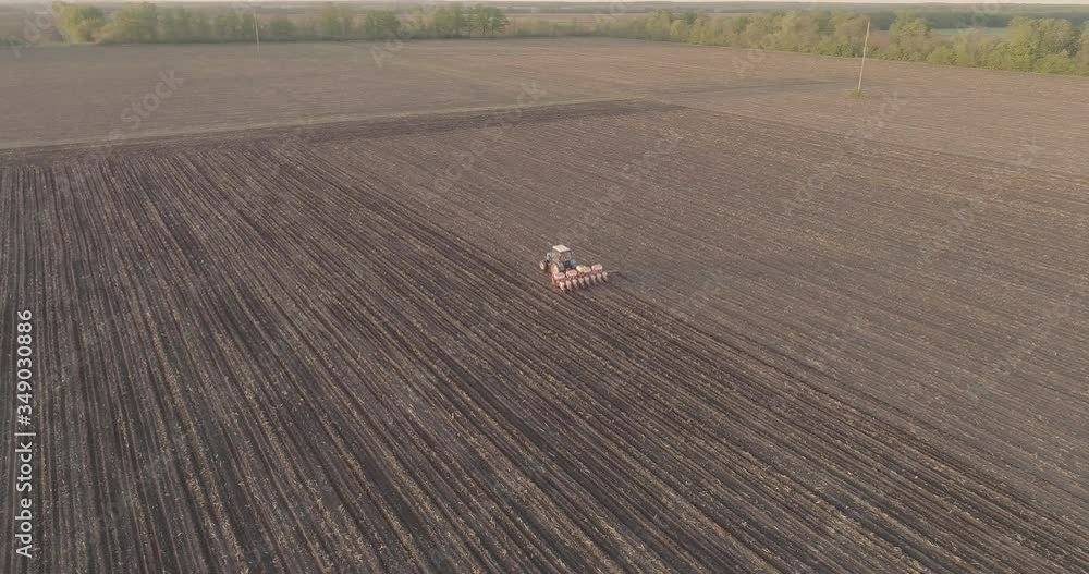 An agricultural tractor carries out work on sowing grain. seasonal work. drone shooting from the air An agricultural tractor carries out work on sowing grain. seasonal work. drone shooting from the air