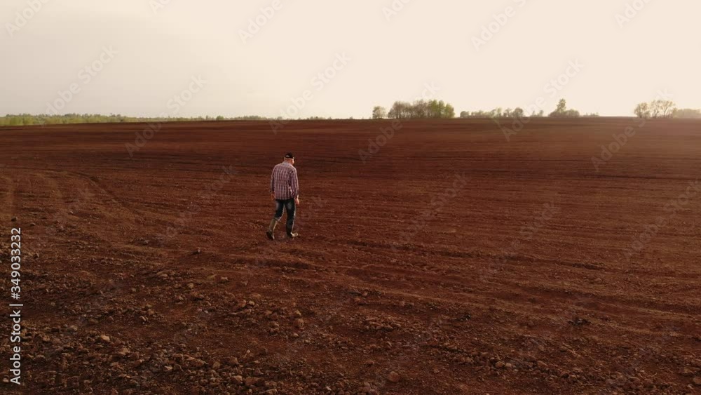 aerial photography the drone follows a farmer walking through a plowed field with land. Fly around and follow farmers top view aerial photography the drone follows a farmer walking through a plowed field with land. Fly around and follow farmers top view
