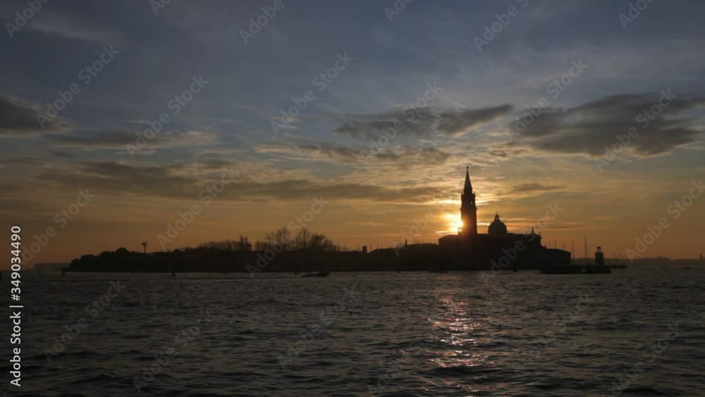 Sun setting behind the bell tower of the church of San Giorgio, Venice, Italy. Concept: sunset over Venice, tranquility and spirituality, travel to famous places Sun setting behind the bell tower of the church of San Giorgio, Venice, Italy. Concept: sunset over Venice, tranquility and spirituality, travel to famous places