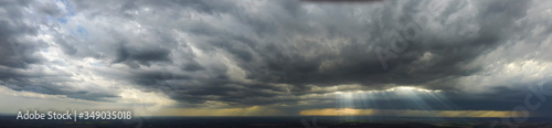 Panorama with a view of the rapidly approaching thunderstorm, the sun's rays shining through the clouds.