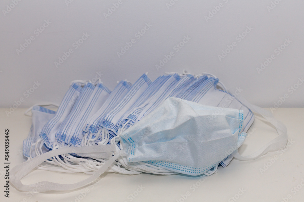 One folded disposable face mask and a pile of masks ready to be used
